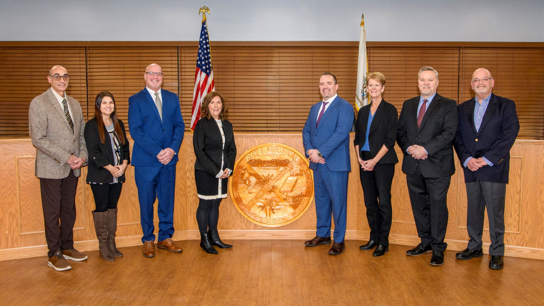 Full board of trustees in front of wooden long desk.