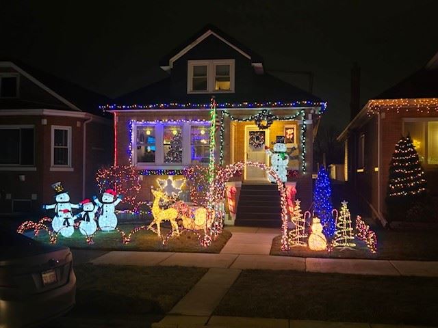 House with lighted snowmen, reindeer, and Christmas trees